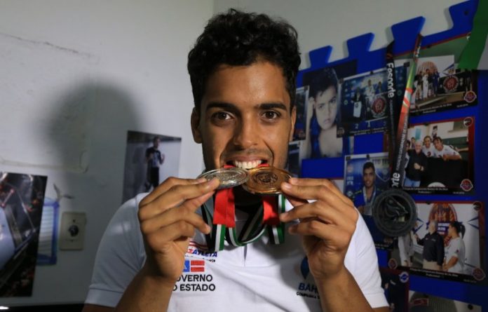 Atleta segurando medalhas entre os dentes